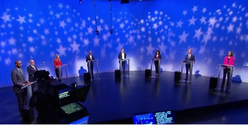 Panelists stand on a stage ahead of a previous debate cycle.